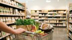 Einkaufswagen mit frischen Lebensmitteln in einem hellen Supermarktgang